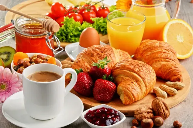Sarapan sehat berlimpah dengan roti, buah-buahan, sayuran, kacang-kacangan, kopi, dan jus