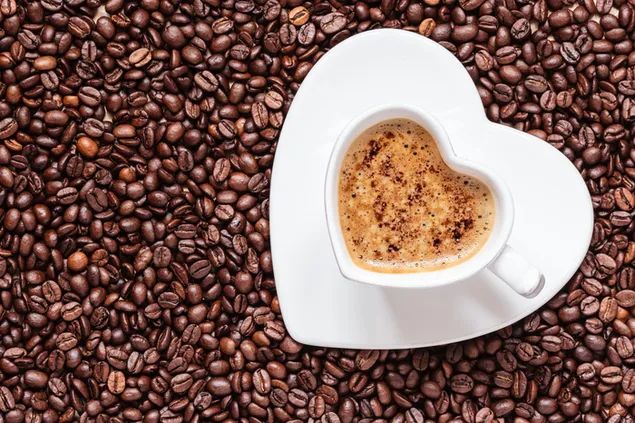 Taza en forma de corazón con café cremoso con granos de café