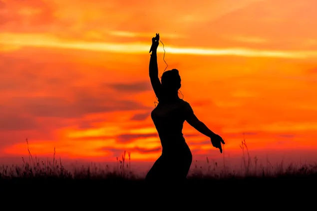Hintergrundbeleuchtungsfoto einer Frau, die Yoga mit Blick auf den roten Himmel macht