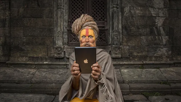 Hombre con la cara pintada sosteniendo una tableta de la marca Apple frente al edificio de piedra