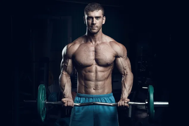 Hombre musculoso guapo levantando pesas en el gimnasio y mostrando todos sus músculos culturista descargar