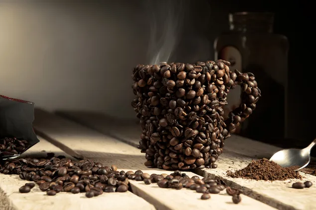 Kopi panas dalam gelas yang terbuat dari biji kopi di atas meja kayu