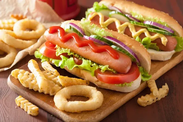 Hotdog-Sandwich mit Ketchup und Senf mit Zwiebelringen und Pommes auf der Seite
