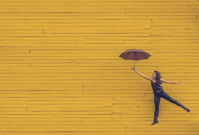 黄色の木製の背景に傘を保持している女の子