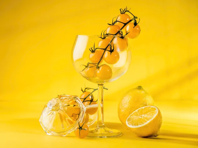黄色のトマトと黄色の背景にガラスのカットレモン