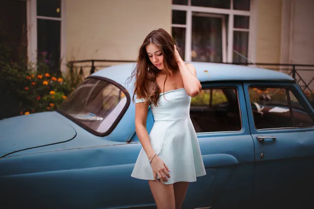 Hübsches Mädchen in pastellgrünem Kleid mit blauem Autohintergrund