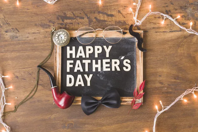 Imagen de celebración del día especial del padre con mini pizarra enmarcada, gafas, pipa, reloj y pajarita negra sobre fondo de madera