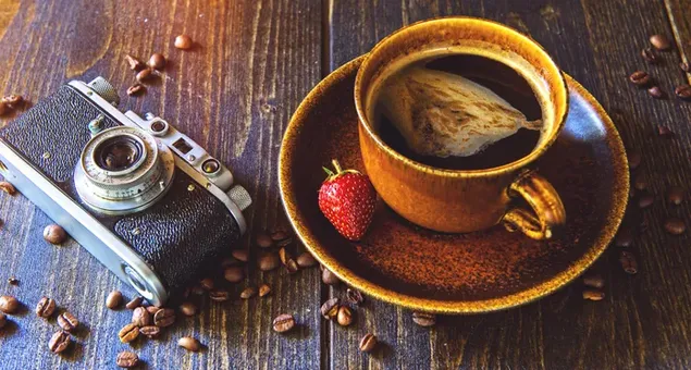 Klassischer Kaffee in einer Tasse mit Erdbeere und einer Kamera an der Seite