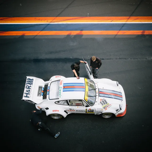 Klassischer weißer Porsche 911 beim Boxenstopp mit Crew