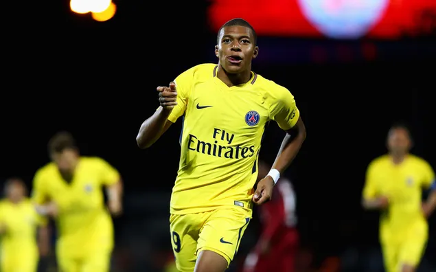 Kylian Mbappe ina seasamh i ngeansaí buí sacair íoslódáil