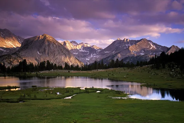 Paisaje de cielo nublado con belleza de hierba y picos nevados de montañas reflejadas en el agua HD fondo de pantalla
