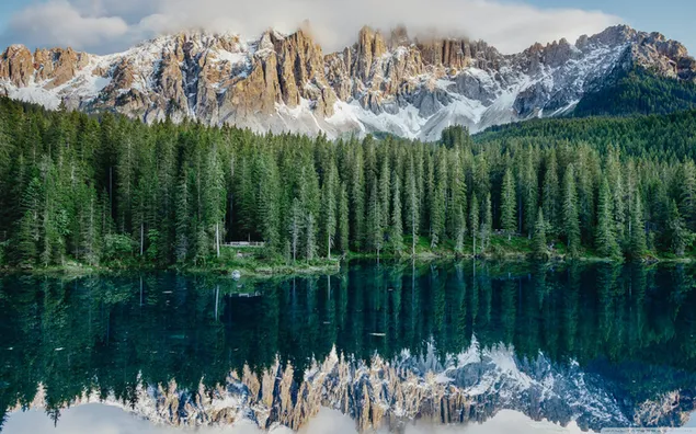 Landschaft mit schneebedeckten Bergen und Wäldern, die sich im See spiegeln 2K Hintergrundbild