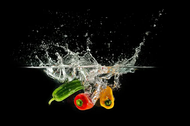 Lebensmittelfotografie, Chili und Paprika, die vor schwarzem Hintergrund ins Wasser fallen herunterladen