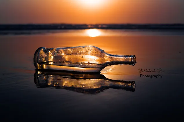 Lege fles op het strand en zonsondergang
