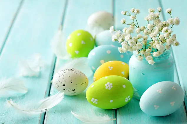 uovo di pasqua azzurro e verde in una tavola di legno blu con un vaso di fiori scarica