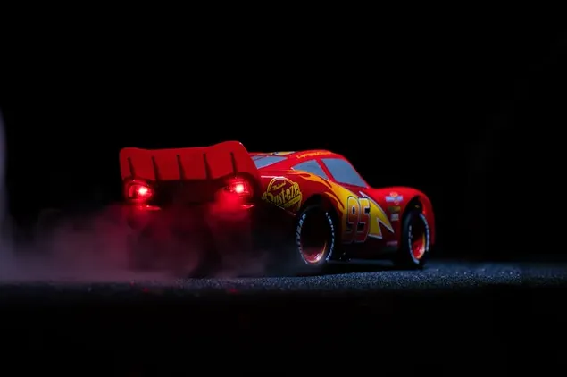 Lightning McQueen, el auto de carreras número 95 en rojo con llantas deportivas anchas, está en la oscuridad.