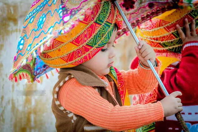 Kleine schattige jongen gekleed in traditionele kleding uit de Indiase cultuur met een kleurrijke hoed die zaken doet download