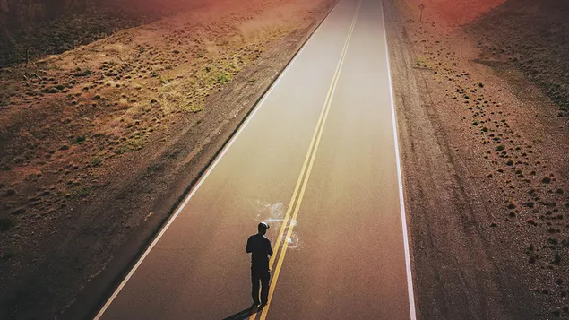 Hombre solitario caminando en medio de una carretera vacía descargar
