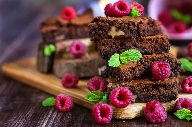 Deliciosos brownies con frambuesa en una tabla de madera 4K fondo de pantalla