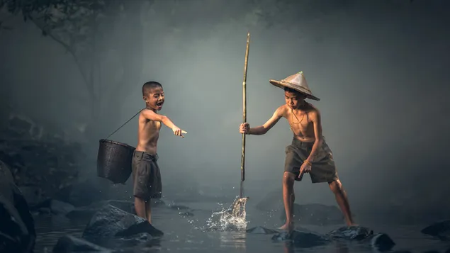 Lustige Momente von zwei Kindern, die im nebligen Wald im Bach fischen herunterladen