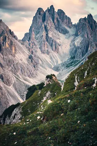 majestic rocky mountain peaks with green grassy slopes under cloudy dramatic blue sky download