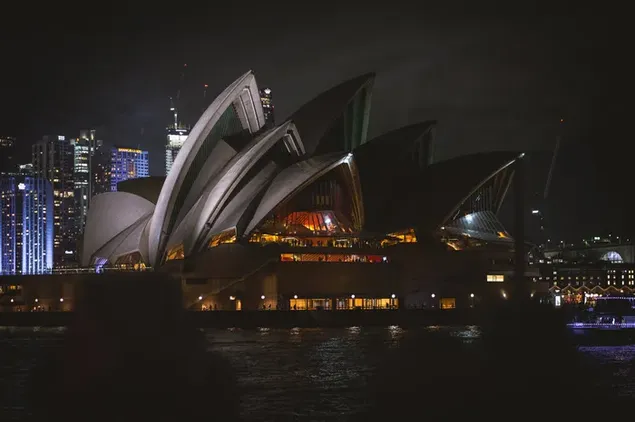 Majestic view of sydney opera house in australia at night among building  lights 4K wallpaper download