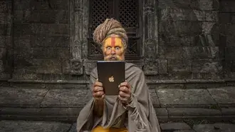 muz s namalovanym oblicejem drzi tablet znacky apple pred kamennou budovou stahnout