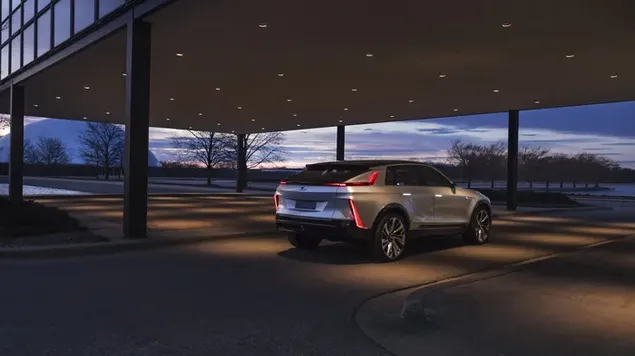 Maravillosa postura del moderno coche deportivo Cadillac con luces de estacionamiento en la carretera asfaltada debajo del edificio