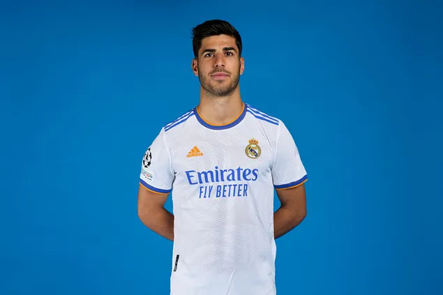 marco asensio posa amb les mans a l'esquena davant d'un fons blau amb una samarreta del reial madrid baixada