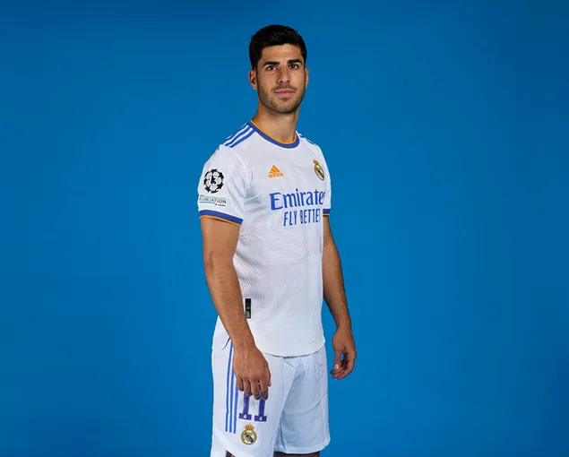 marco asensio posa de peu davant d'un fons blau amb una samarreta del reial madrid baixada