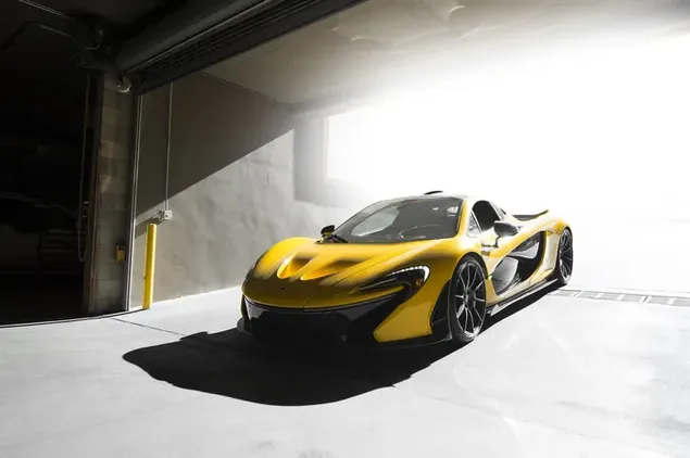 mclaren-sportmotor met geel en swart kleur en staalwiele met sy wonderlike ontwerp staan   in 'n toe motorhuis geparkeer aflaai