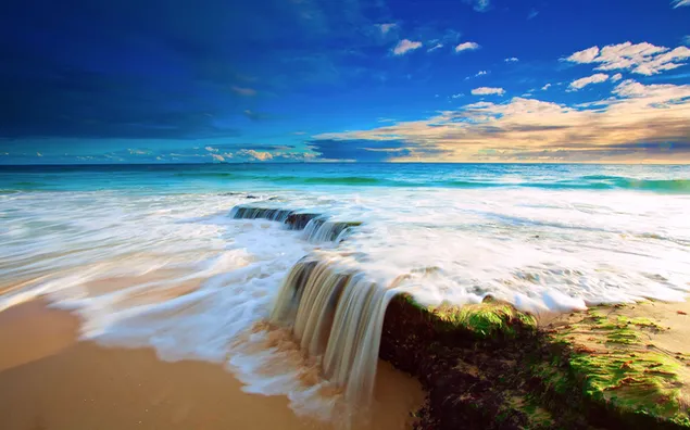 Meereswellen, die sich bei bewölktem Wetter bis zum Strandsand erstrecken
