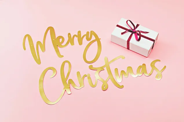 Felices saludos navideños y un regalo en un fondo rosa. 6K fondo de pantalla