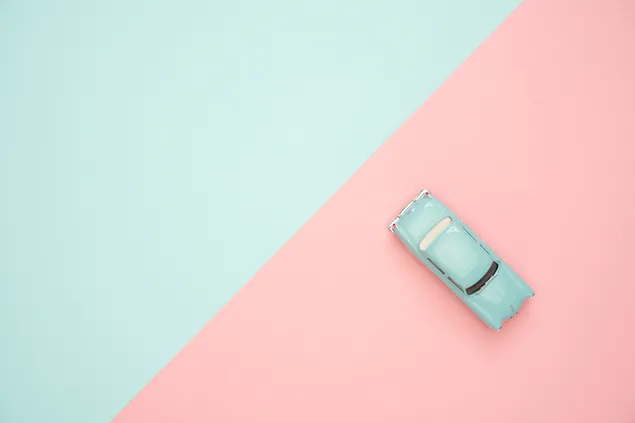 Miniatur mobil klasik dengan latar belakang biru muda dan merah muda