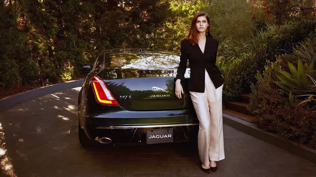 Model Alexandra Daddario Kleid in legerer Schräglage in einem Jaguar Auto