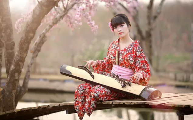 木々や花のある庭で楽器を演奏する赤いドレスを着た女性の着物