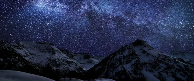 Nachtaufnahme von schneebedeckten Bergen, die von Sternenlicht beleuchtet werden