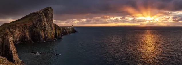Mercusuar Neist Point di bebatuan, Isle of Skye, Skotlandia dan laut dengan sinar matahari yang dipantulkan