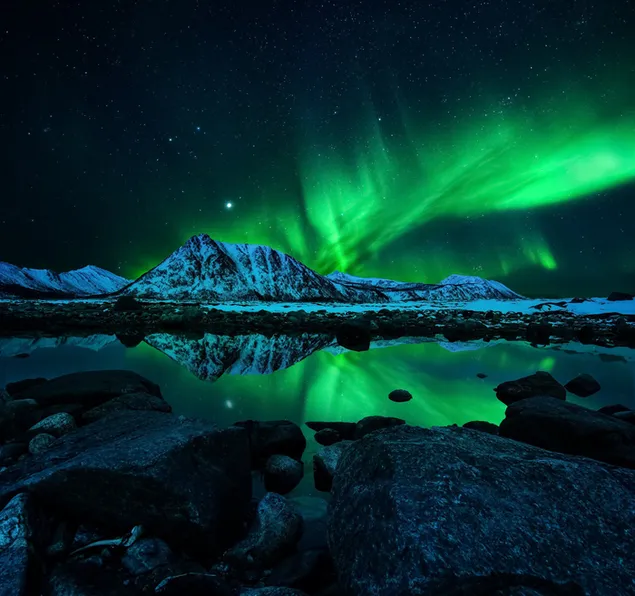 Aurora boreal y reflejo del lago de las montañas nevadas
