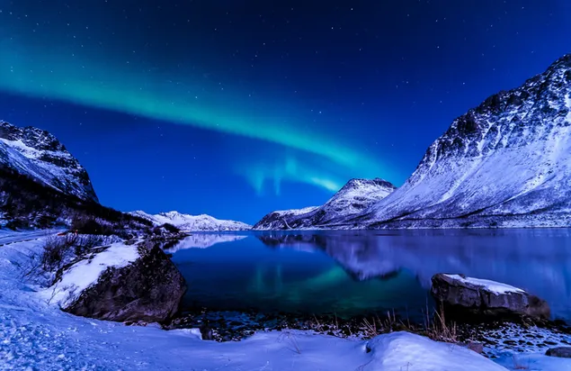 Las auroras boreales son resplandores naturales en la noche, con rocas cubiertas de nieve y su luz reflejada en el agua.
