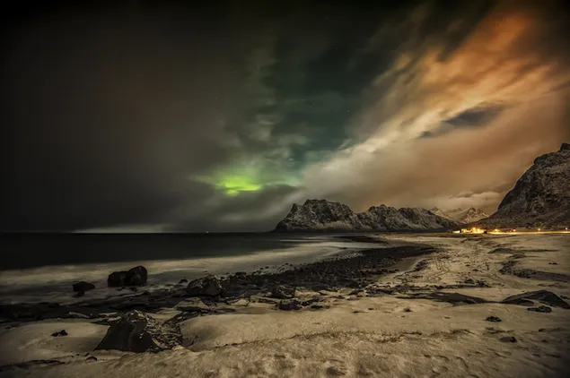 Northern lights exposed in fog behind cliffs and sand