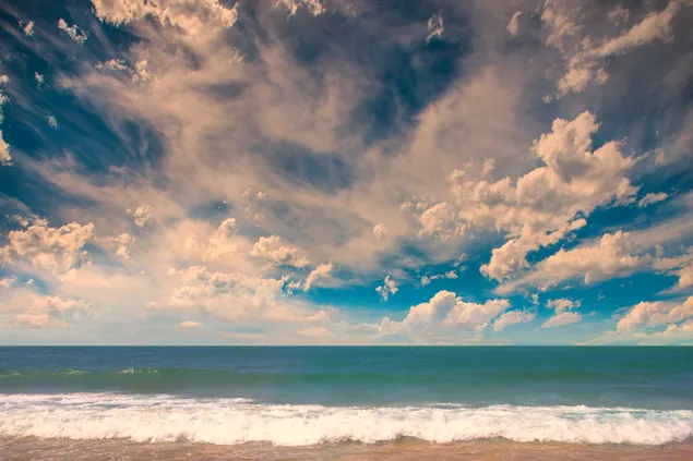 Olas del océano golpeando la playa en tiempo nublado 2K fondo de pantalla