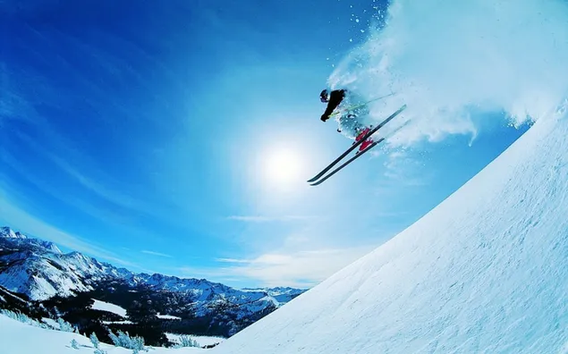 Olahragawan snowboarding di salju di antara pegunungan pada saat matahari sedang tinggi unduhan