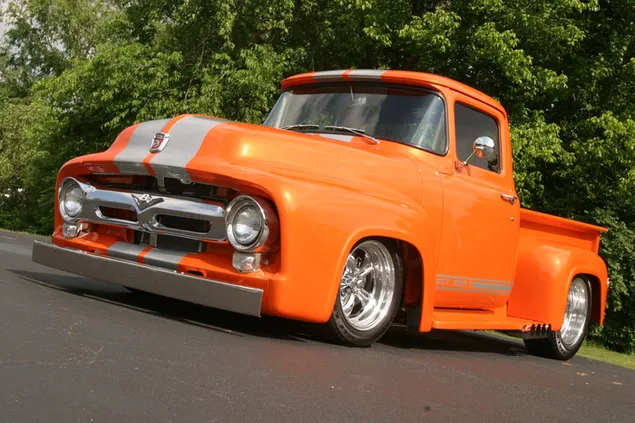 Orange farve vintage pickup truck parkeret på en træforet vej 2K tapet