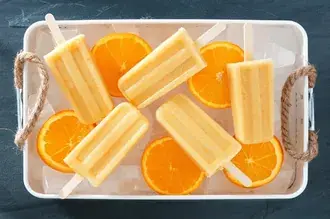오렌지 슬라이스가 있는 흰색 쟁반에 담긴 오렌지 맛 아이스 캔디 4K 배경화면