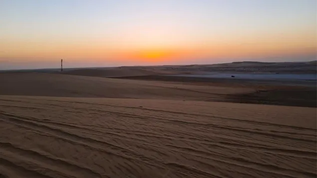 Oranje zonsondergang boven een kalme woestijn