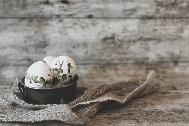 uovo di pasqua dipinto in una ciotola con tappeto in una vecchia fotografia grunge plancia di legno scarica