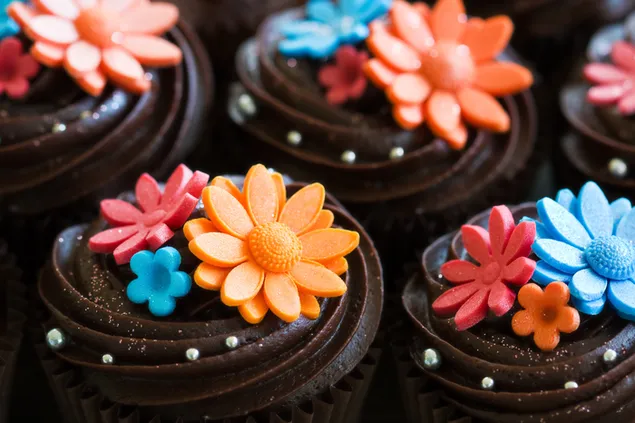 Pastelería: glaseado de fondant de flores comestibles de colores sobre glaseado de chocolate