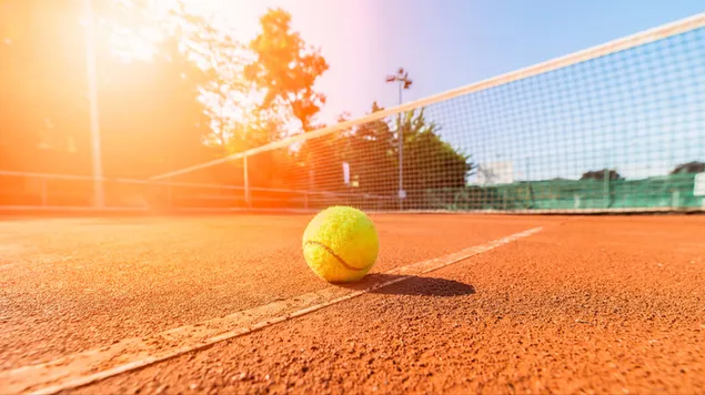 Pelota de tenis de pie en la cancha de tenis de tierra batida en un día soleado
