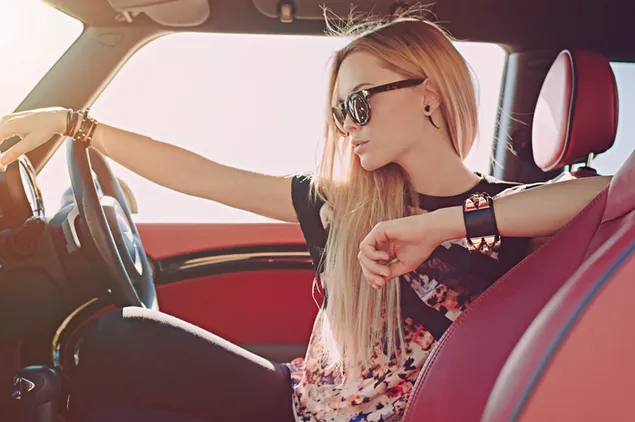 Petite blonde long haired girl inside a car with red interior